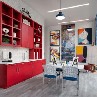 A modern kitchen and dining area with bold red cabinetry and vibrant artwork on the walls.