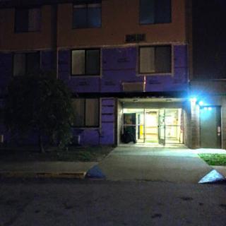 A view of a building entrance illuminated by blue light at night.