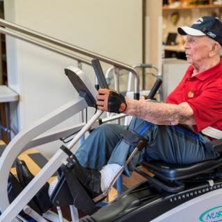 An elderly person actively exercising on gym equipment, highlighting a commitment to fitness and health.