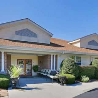 A well-maintained building entrance with neatly trimmed bushes and outdoor seating.