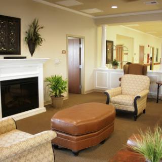 A cozy and inviting living room space featuring comfortable chairs, an ottoman, and a fireplace.