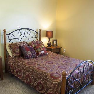A cozy bedroom with a decorative metal-framed bed, patterned bedding, and a bedside lamp.