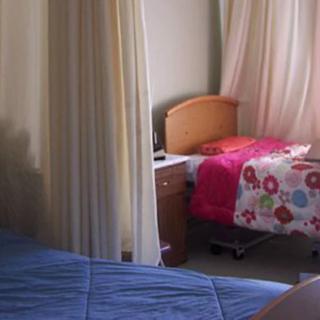 A hospital room with two beds separated by a privacy curtain.