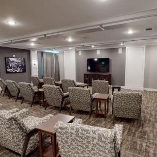 A modern theater room with multiple rows of comfortable seating and a large television.