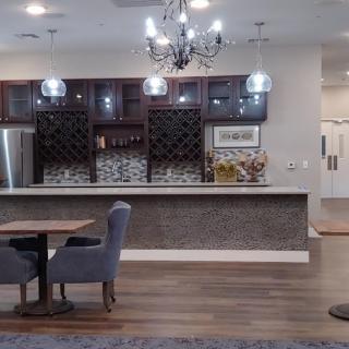 A modern bar area with wine racks and a chandelier, featuring stylish seating and wood flooring.