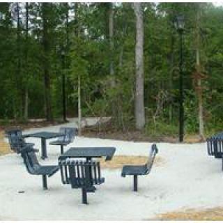 An outdoor picnic area with tables and benches surrounded by a forest.