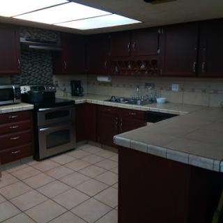A modern kitchen featuring wooden cabinets, stainless steel appliances, and a spacious countertop.