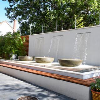 A serene outdoor fountain featuring three concrete bowls, creating a tranquil ambiance with flowing water.