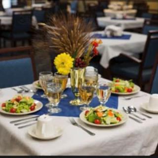 A beautifully set dining table with salads, glasses, and a floral centerpiece in a restaurant.