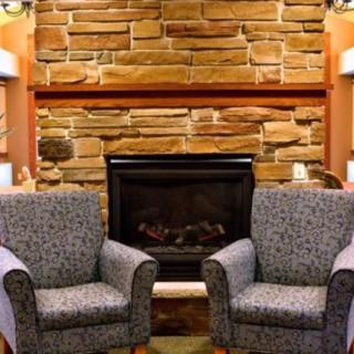 A cozy indoor setting featuring two armchairs in front of a stone fireplace.