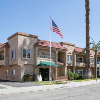 A two-story building with an American flag and palm trees on a sunny day.