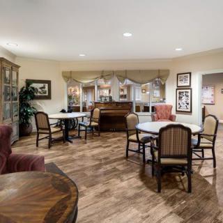 A cozy dining area with multiple tables and chairs, warm lighting, and decorative elements.
