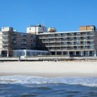 A beachfront hotel with a clear blue sky and gentle ocean waves.