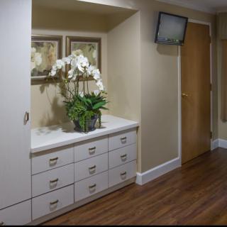 A hallway with a set of drawers and decorative accents, including orchids and paintings.