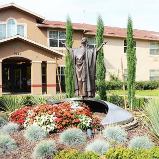 A statue surrounded by a beautifully landscaped garden in front of a building.