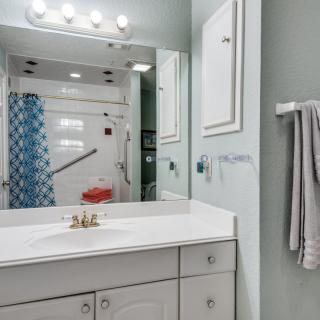 A modern bathroom with a sink, mirror, and shower area.