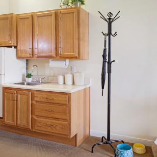 A kitchen area with wooden cabinets and a coat rack holding an umbrella.