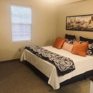 A cozy bedroom with a well-decorated bed, featuring vibrant pillows and wall art.