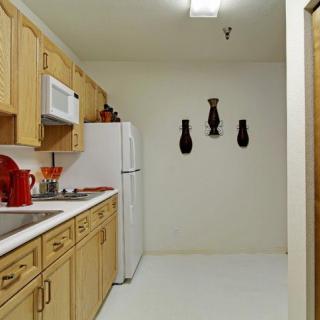A modern kitchen with wooden cabinets, a white refrigerator, and decorative wall vases.