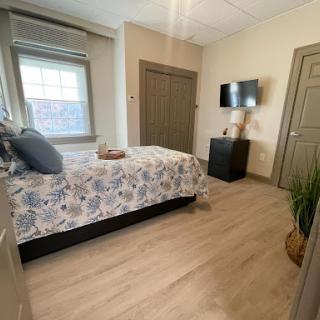 A cozy and well-decorated bedroom featuring a floral bedspread, modern furnishings, and natural light.