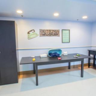 A minimalist office space featuring a table with various items, and artwork on the wall.