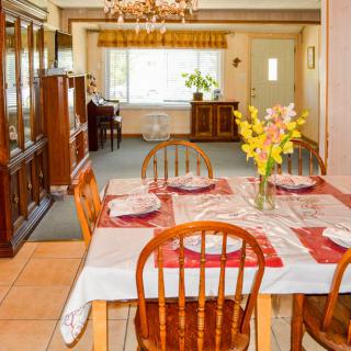 A cozy dining room with a wooden table set for four, adorned with a floral centerpiece and surrounded by matching chairs, beneath a chandelier.