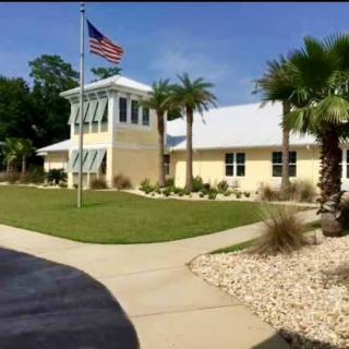 A building with an American flag and palm trees, surrounded by well-maintained landscaping on a sunny day.