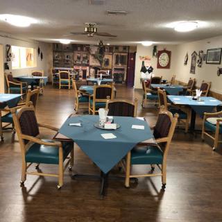 An empty dining room with arranged tables and chairs, decorated in a cozy style.