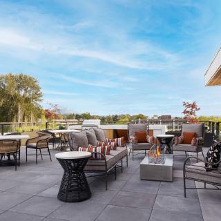 Modern outdoor patio with comfortable seating and a central firepit, set against a scenic landscape.