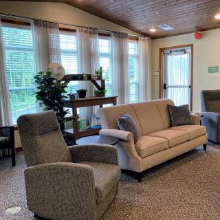 A cozy living room with comfortable seating, large windows allowing natural light, and lush green plants adding a touch of nature.