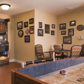A cozy game room featuring a dartboard, wall art, and comfortable seating arrangements.