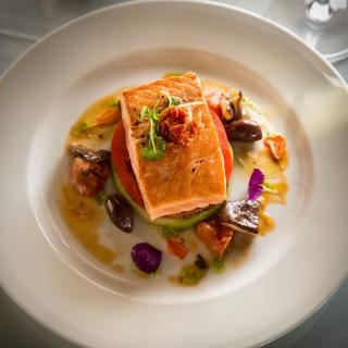 A beautifully plated gourmet dish featuring salmon and vegetables.