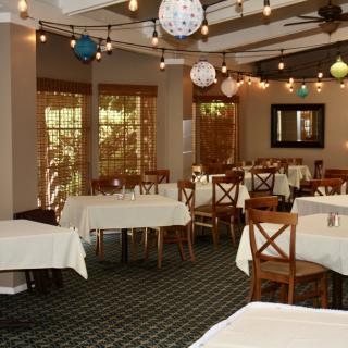 An elegantly decorated restaurant dining room with tables and chairs, adorned with decorative lighting.