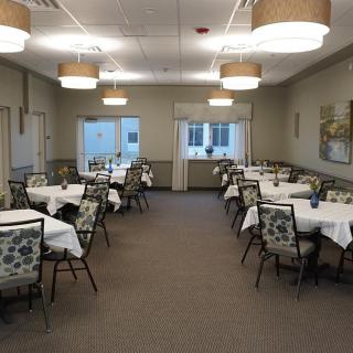 A formal dining room with neatly arranged tables and chairs, featuring elegant lighting and decor.