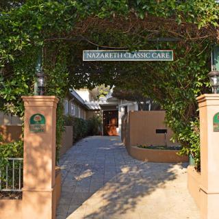 A charming entrance to a cafe, surrounded by lush greenery and inviting pathways.