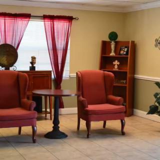 A cozy living room with two red chairs, a small table, and decorative elements on a shelf.