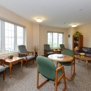 A cozy living room with several chairs, tables, and a sofa arranged near large windows.