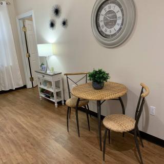 Cozy dining nook with a small table and chairs, accented by a wall clock and indoor plant.