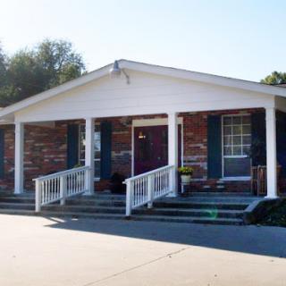 A charming brick house with a welcoming porch and steps leading to the entrance.