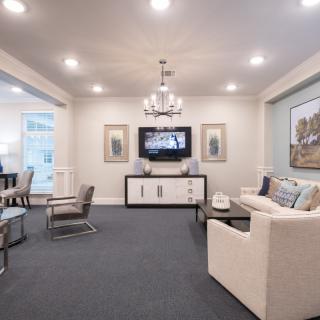 A modern and elegantly decorated living room with a chandelier, comfortable seating, and stylish wall art.