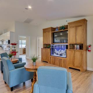 A cozy living room with blue chairs and a wooden entertainment center featuring a TV and aquarium.