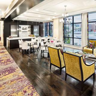 A modern open-concept living and dining area with a kitchen, featuring stylish furniture and large windows that provide ample natural light.