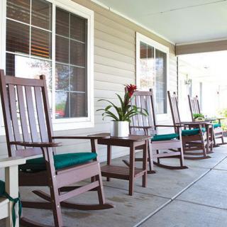 A cozy porch with rocking chairs and a potted plant.