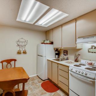 A cozy kitchen with wooden cabinets, a small dining table, and essential appliances.