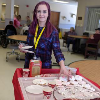 A volunteer serving food to residents at a senior care facility.