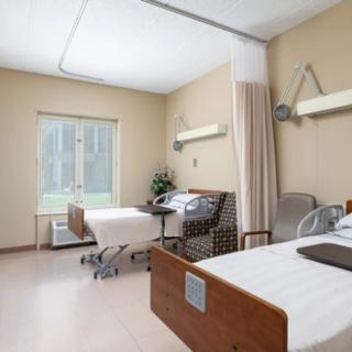 A hospital room with two patient beds and medical equipment.