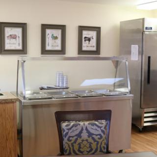 An interior view of a kitchen area featuring a food service counter and decorative artwork.