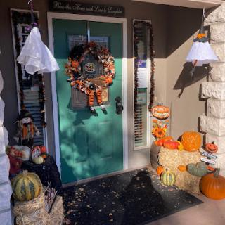 A cozy front porch adorned with festive Halloween decorations, featuring pumpkins and a seasonal wreath.