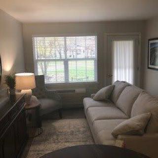 A cozy living room with a sofa, chair, and lamp near a window.