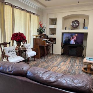 A cozy living room featuring a piano, comfortable seating, and a television.